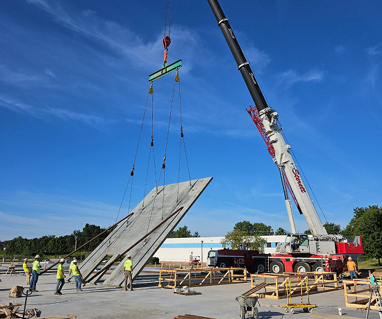 a crane in use to move a large concrete slab from horizontal to vertical